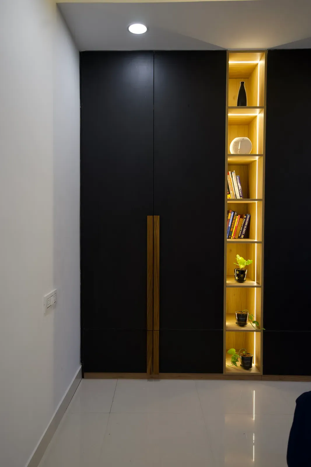 Black wardrobe with lit open shelving — The Aakar